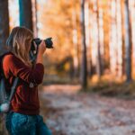 A woman taking photos in an autumn forest, perfectly capturing the beauty of nature.